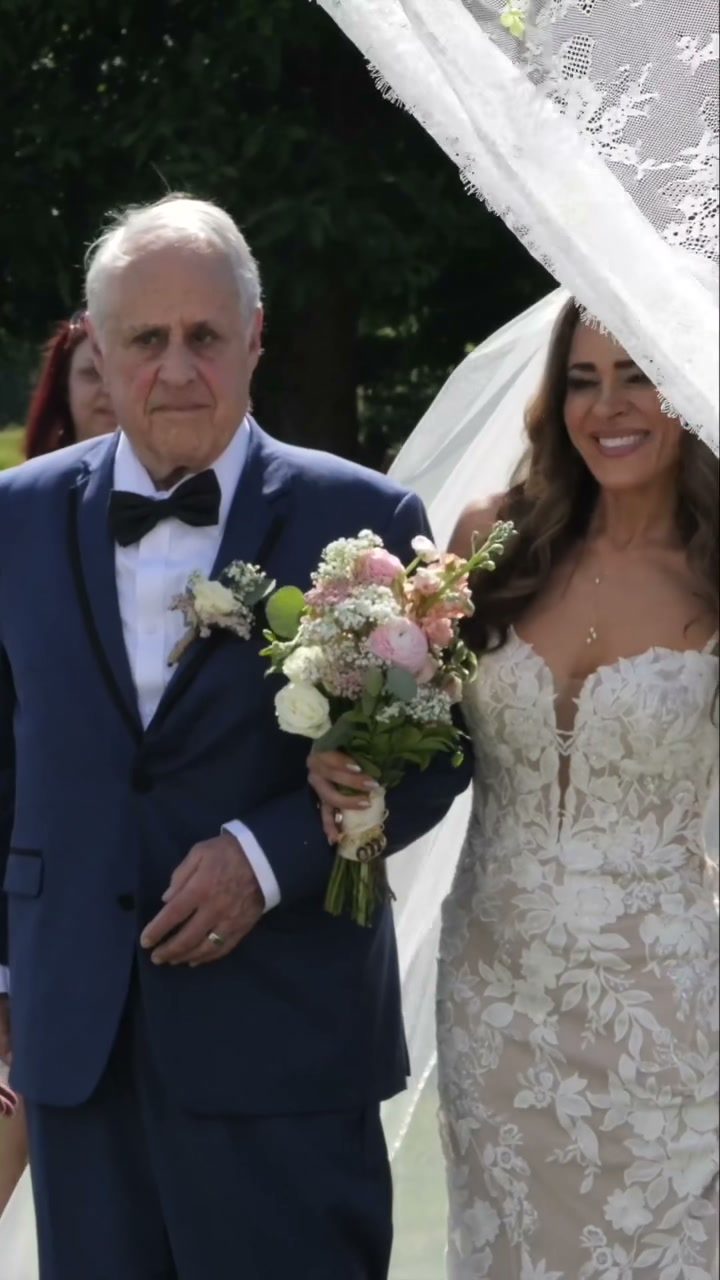 Bride walking down aisle with father framed by lace veil